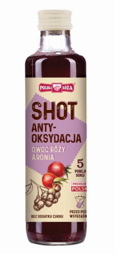 Szklana przezroczysta butelka z białym zakręcanym korkiem, wypełniona mieszanką soków: aronii i dzikiej róży w kolorze ciemnoczerwonym. Na etykiecie znajduje się napis „SHOT Anty-oksydacja ”z  ilustracją aronii i owocu róży.