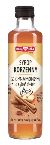 Szklana przezroczysta butelka z czarnym zakręcanym korkiem, wypełniona syropem w kolorze beżowym z etykietą „Syrop korzenny Cynamon cejloński” i ilustracją jabłka i cynamonu. Przeznaczony do herbaty, wody, grzańca.